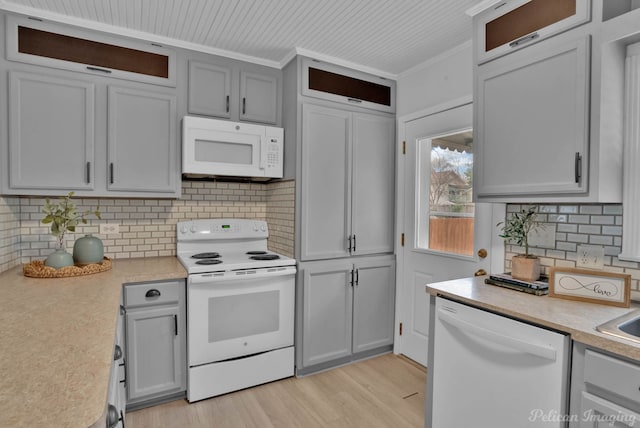 kitchen with light wood finished floors, tasteful backsplash, crown molding, light countertops, and white appliances