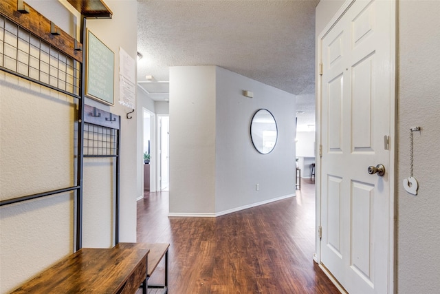 corridor with dark hardwood / wood-style flooring and a textured ceiling