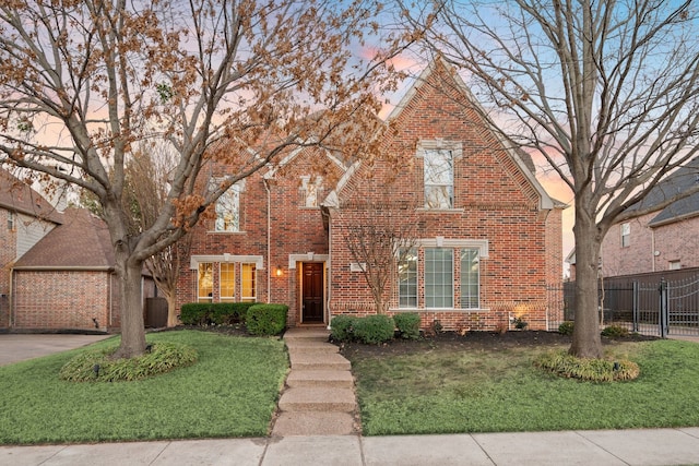 view of front of property with a yard, brick siding, fence, and driveway