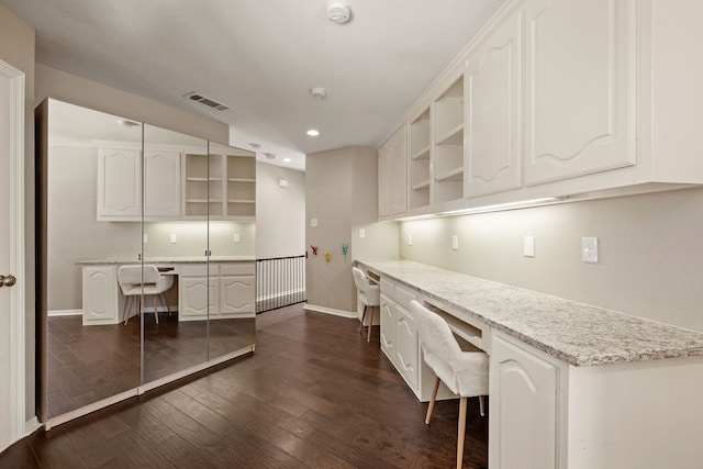 unfurnished office with dark wood-style floors, built in desk, recessed lighting, visible vents, and baseboards