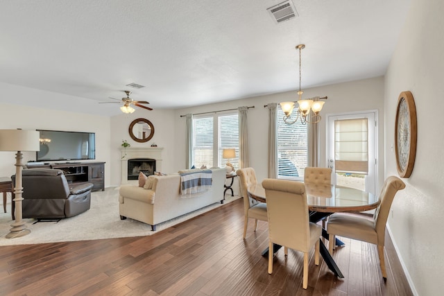 dining area featuring a textured ceiling, hardwood / wood-style flooring, and ceiling fan with notable chandelier