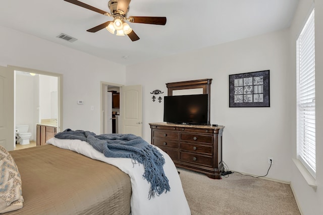 carpeted bedroom with ceiling fan and ensuite bath