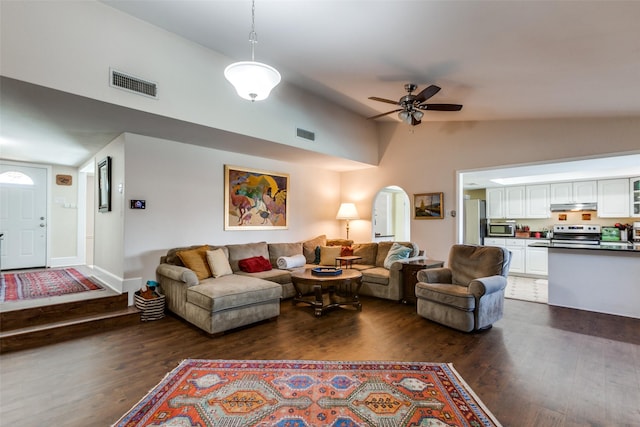 living room featuring visible vents, arched walkways, and dark wood-style flooring