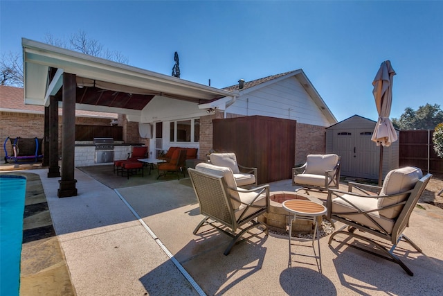 view of patio / terrace with an outbuilding, an outdoor fire pit, a grill, a shed, and exterior kitchen