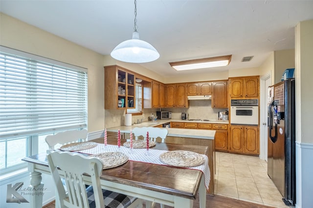 kitchen featuring white appliances, light tile patterned floors, sink, pendant lighting, and kitchen peninsula