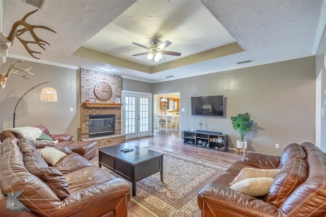 living room with ornamental molding, a raised ceiling, french doors, and hardwood / wood-style floors