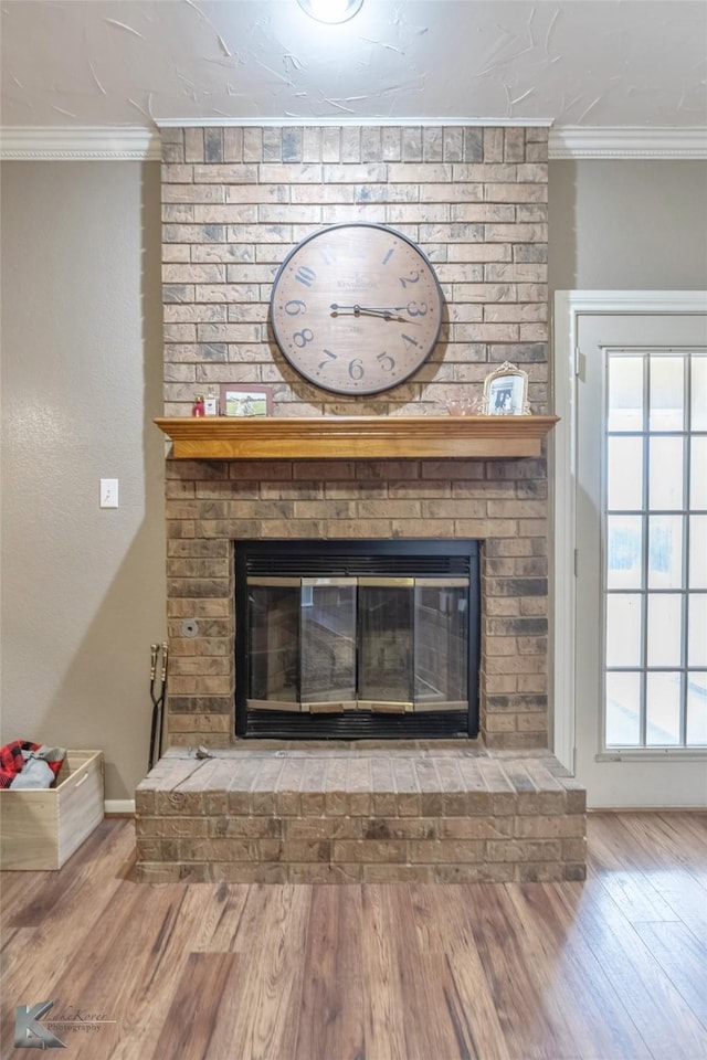 interior details with a brick fireplace, wood-type flooring, and crown molding