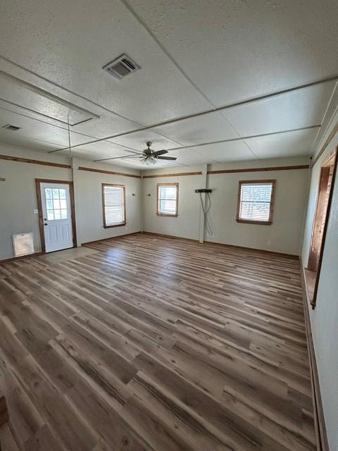 empty room with ceiling fan, dark wood-type flooring, and a textured ceiling