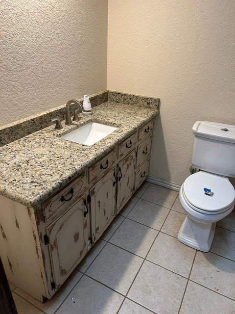 bathroom with toilet, vanity, and tile patterned flooring