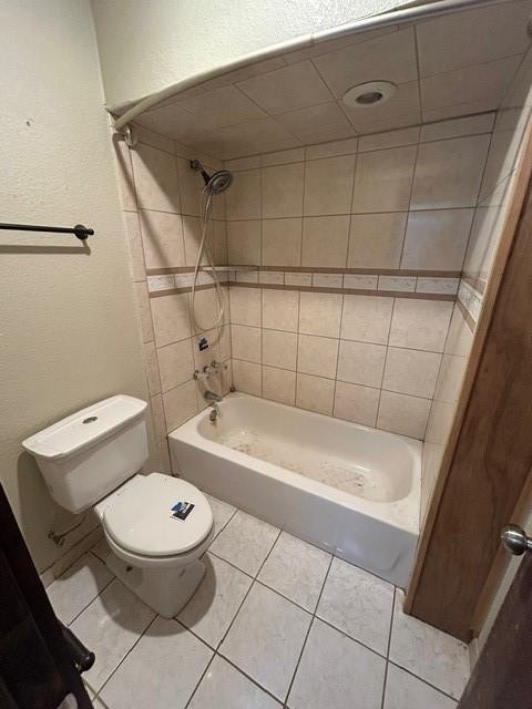 bathroom with tiled shower / bath combo, tile patterned flooring, and toilet