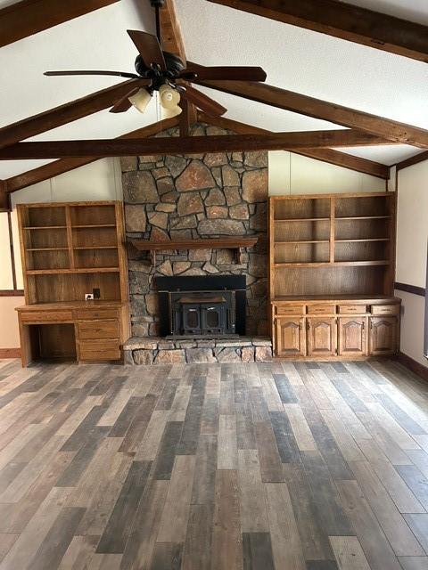 unfurnished living room with ceiling fan, vaulted ceiling with beams, and dark hardwood / wood-style floors