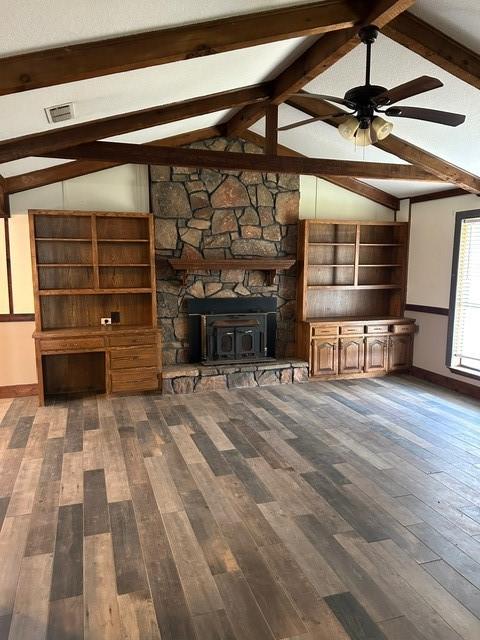 unfurnished living room with ceiling fan, vaulted ceiling with beams, dark wood-type flooring, and a fireplace