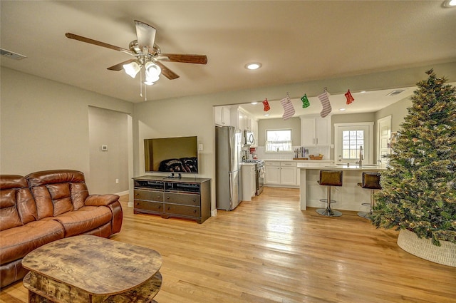 living room featuring light wood-type flooring, sink, and ceiling fan