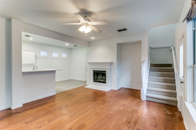 unfurnished living room with light wood-type flooring and ceiling fan