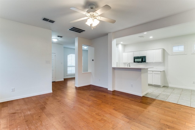 kitchen with ceiling fan, light wood-type flooring, white cabinetry, and kitchen peninsula