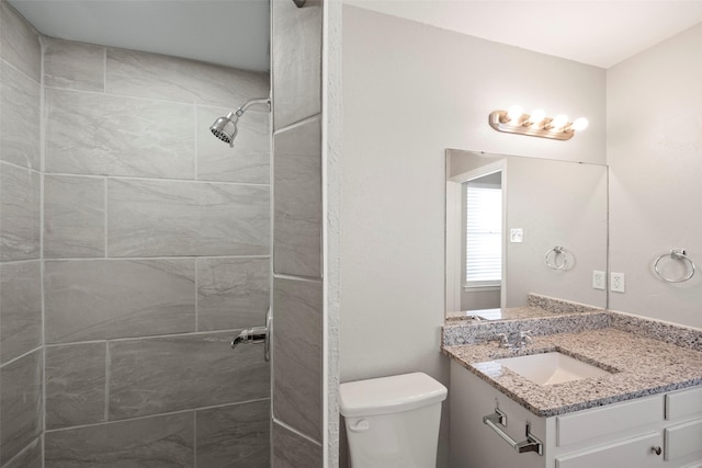 bathroom with vanity, a tile shower, and toilet