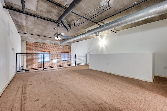 unfurnished room featuring brick wall, carpet flooring, and ceiling fan