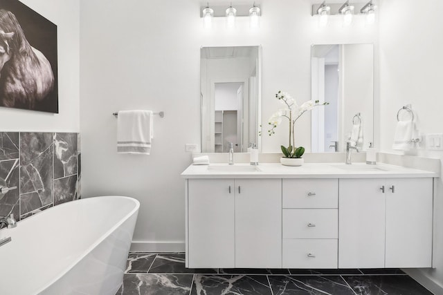 bathroom with marble finish floor, double vanity, a soaking tub, and a sink