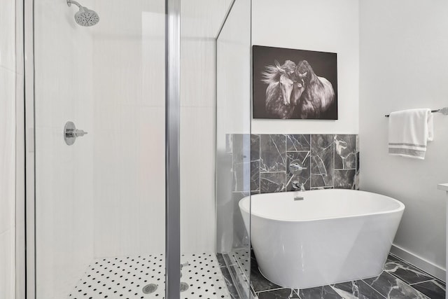 full bath featuring a stall shower, marble finish floor, and a freestanding tub