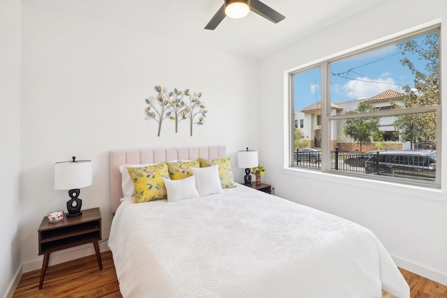 bedroom featuring a ceiling fan, baseboards, and wood finished floors