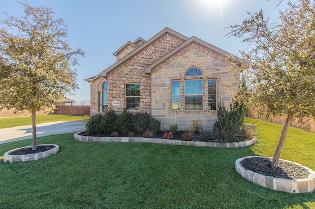 view of front of property with brick siding, stone siding, fence, and a front yard