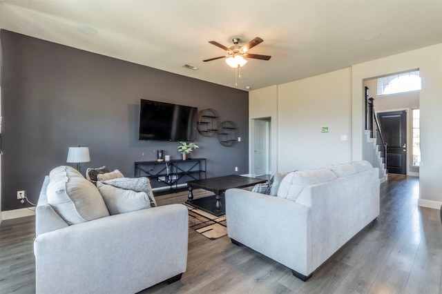 living area featuring wood finished floors, visible vents, baseboards, and stairs