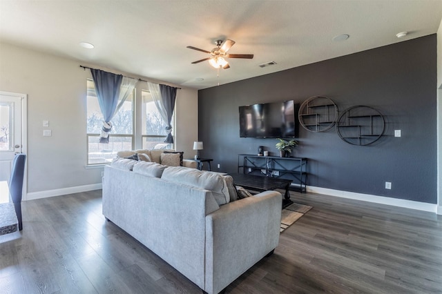 living area featuring ceiling fan, visible vents, baseboards, and dark wood finished floors