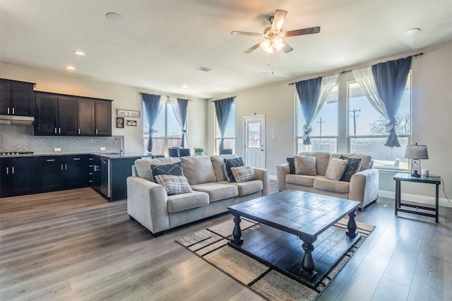 living area with light wood finished floors, baseboards, visible vents, and ceiling fan