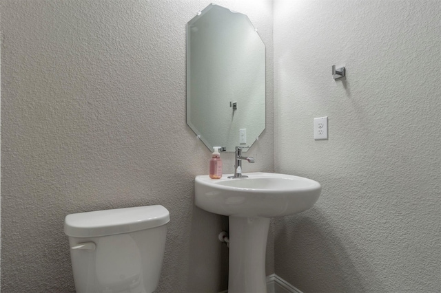 bathroom with toilet and a textured wall