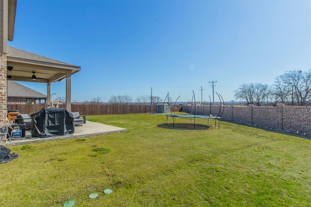 view of yard featuring a trampoline, a fenced backyard, a patio, and ceiling fan