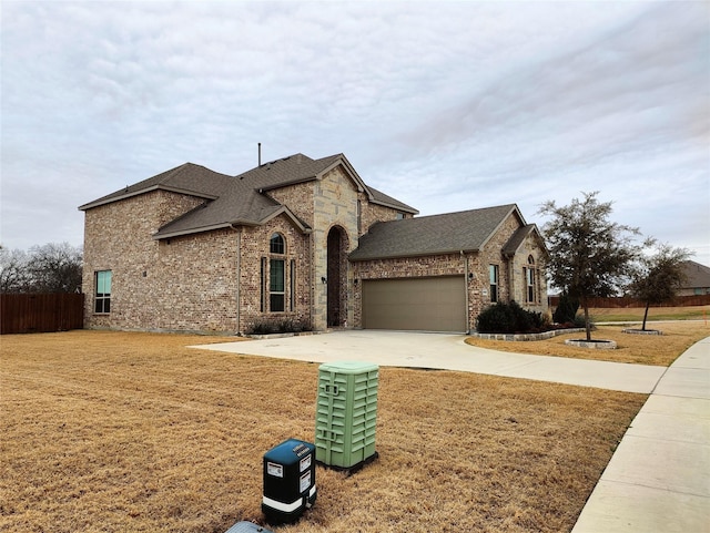 french country home with concrete driveway, roof with shingles, an attached garage, fence, and a front yard