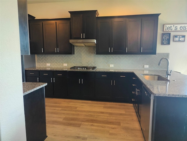 kitchen with light wood-type flooring, a sink, light stone countertops, and under cabinet range hood