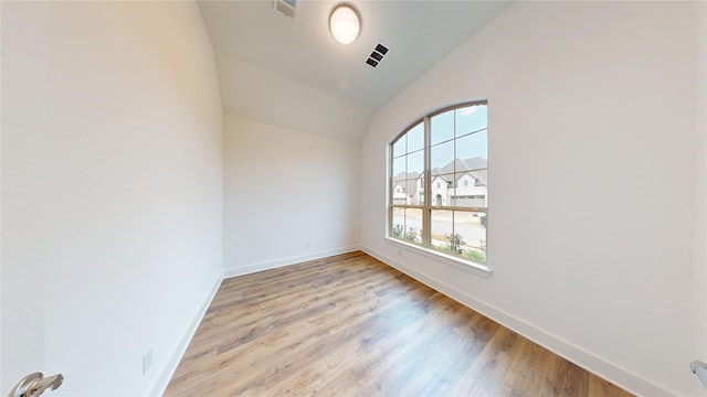 spare room with light hardwood / wood-style floors and lofted ceiling