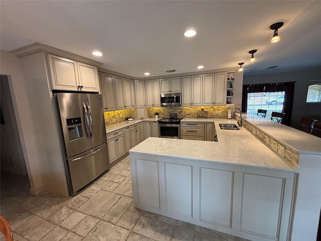 kitchen with kitchen peninsula, stainless steel appliances, sink, backsplash, and light stone counters