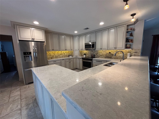 kitchen with sink, light stone counters, stainless steel appliances, kitchen peninsula, and decorative backsplash