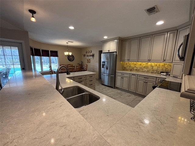 kitchen with tasteful backsplash, gray cabinetry, stainless steel refrigerator with ice dispenser, pendant lighting, and sink