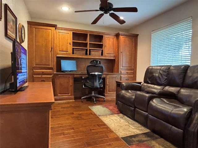 office with dark wood-type flooring, built in desk, and ceiling fan