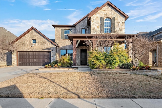 french provincial home with stone siding, brick siding, and driveway