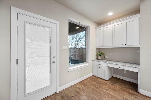 unfurnished office with recessed lighting, built in study area, light wood-type flooring, and baseboards