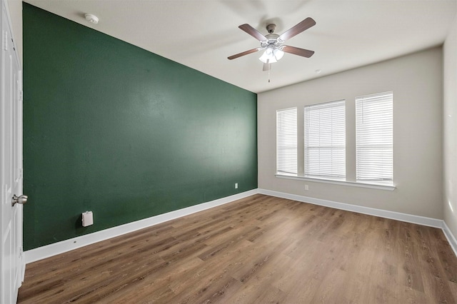 empty room with wood finished floors, baseboards, and ceiling fan