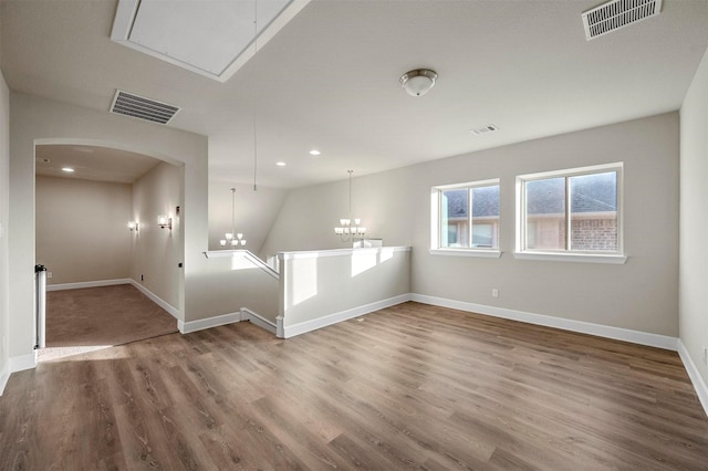 empty room with visible vents, baseboards, attic access, and wood finished floors