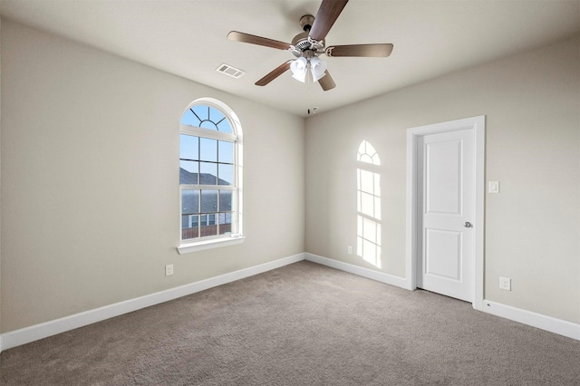 carpeted empty room featuring visible vents, baseboards, and ceiling fan