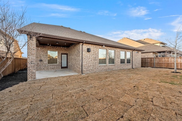 rear view of house featuring a patio area, a yard, a fenced backyard, and brick siding