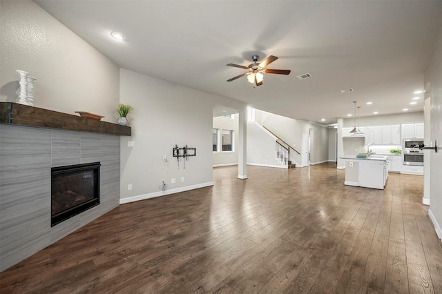 unfurnished living room featuring visible vents, a ceiling fan, hardwood / wood-style floors, a fireplace, and baseboards