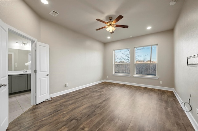 unfurnished room with a sink, wood finished floors, visible vents, and ceiling fan