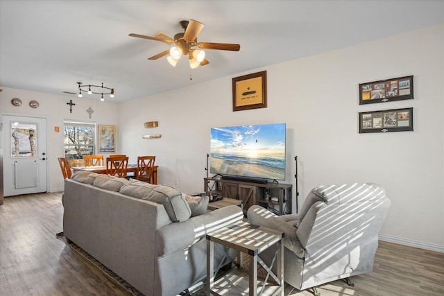 living room featuring baseboards, a ceiling fan, and wood finished floors