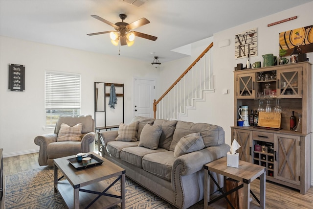 living room with ceiling fan, visible vents, stairway, and wood finished floors