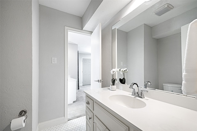2529 Guerrero Dr, Carrollton, TX 75006 - bathroom featuring a textured wall, visible vents, toilet, vanity, and baseboards