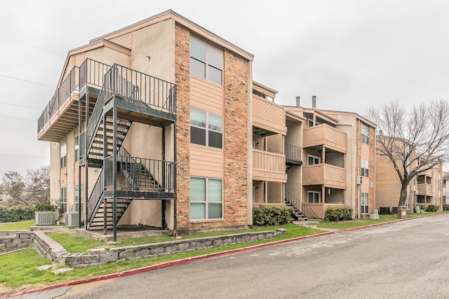 view of property with central air condition unit and stairway