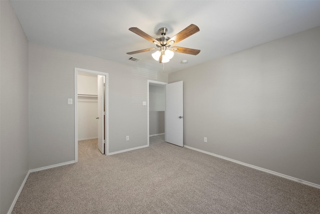 unfurnished bedroom with light carpet, a closet, ceiling fan, and a spacious closet